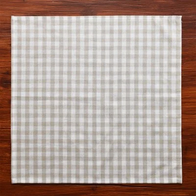 Ein quadratisches, beige-weiß kariertes Tuch, das von oben betrachtet auf einer Holzfläche ausgebreitet ist.