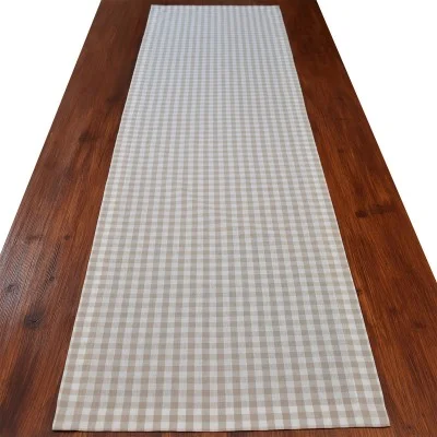 Ein braun-weiß karierter Tischläufer 140 cm lang auf einem langen Holztisch, von oben gesehen.