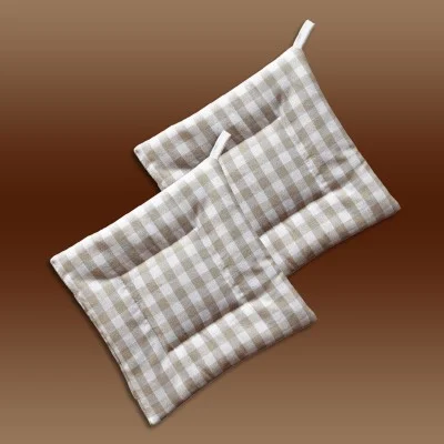 Zwei beige-weiß karierte, gesteppte Topflappen mit Schlaufen, die sich auf einem Hintergrund mit braunem Farbverlauf überlappen.