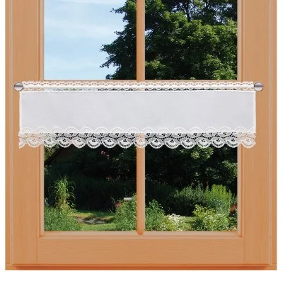 Ein holzgerahmtes Fenster mit einem weißen Spitzenvorhang mit Wellenschliff. Draußen sieht man grüne Bäume, Sträucher und einen sonnenbeschienenen Garten unter blauem Himmel. Der Vorhang hängt in der Mitte und lässt das natürliche Licht herein.