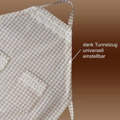 Abgebildet ist eine beige-weiß karierte Schürze mit Spitzenbesatz auf der Brust und der Tasche. In der oberen Ecke befindet sich eine Schlaufe. Der deutsche Text mit einem Pfeil lautet: "Dank Tunnelzug universell einstellbar".