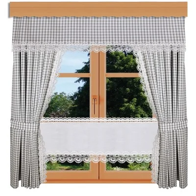 Ein holzgerahmtes Fenster mit grau-weiß karierten Vorhängen, Spitzenbesatz und einem passenden Volant. Durch die Glasscheiben sind draußen grüne Bäume und Gras zu sehen.