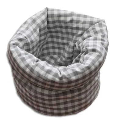 Ein weicher, runder Stoffkorb mit grau-weißem Karomuster, gepolsterten Seiten und offener Oberseite vor weißem Hintergrund.