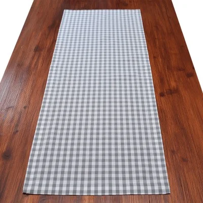 Ein Holztisch mit einem grau-weiß-karierten Tischläufer in der Mitte.