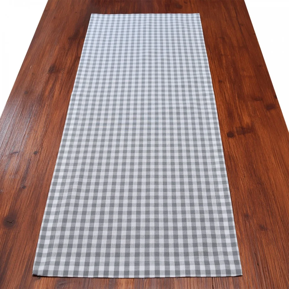 Ein Holztisch mit einem grau-weiß-karierten Tischläufer in der Mitte.