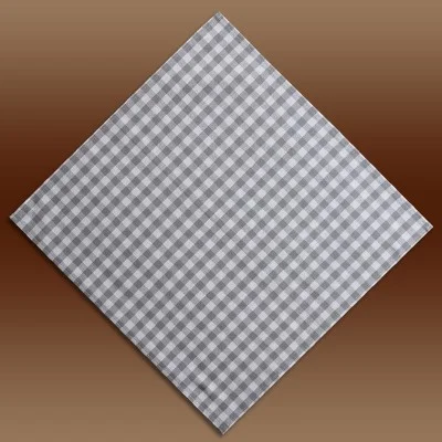 Eine grau-weiß karierte Serviette ist rautenförmig auf einem braunen Hintergrund mit Farbverlauf angeordnet.