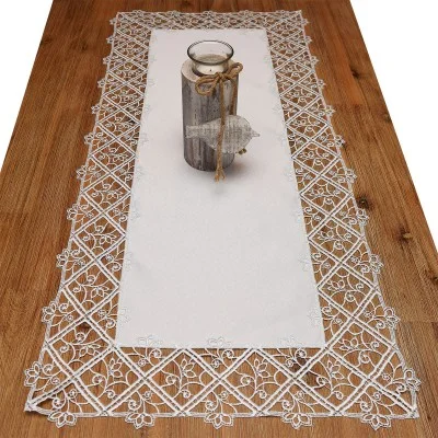 Ein Holztisch mit einem Tischläufer aus weißer Spitze, der ein florales Muster aufweist. In der Mitte des Tisches steht ein hölzerner Kerzenständer, der mit Schnur befestigt und mit einem kleinen hölzernen Fisch verziert ist.