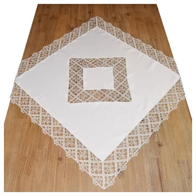 Ein weißes, quadratisches Tischtuch mit detaillierten Spitzenbordüren und ein passendes, mit Spitze eingefasstes Quadrat, das diagonal auf einem Holzboden liegt. Die Spitze zeigt feine geometrische und florale Motive.