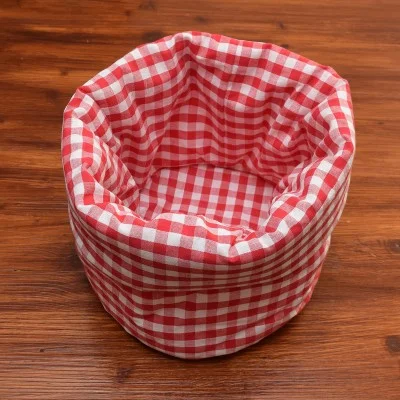 Ein runder Stoffkorb mit einem rot-weiß karierten Muster steht auf einer Holzfläche. Der Korb ist leer und seine weichen Seiten sind leicht zerknittert.