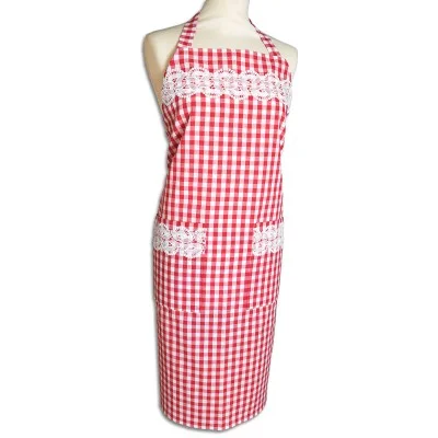 Eine Schaufensterpuppe trägt eine rot-weiß karierte Schürze mit einem Neckholder. Die Schürze ist mit weißer Spitze über der Brust und über zwei Vordertaschen verziert. Das Kleidungsstück ist ganz lang und reicht von der Brust bis zu den Knien.