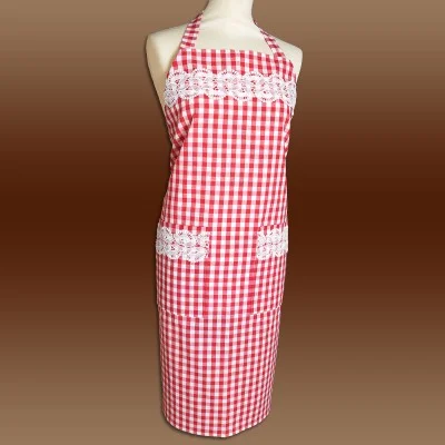 Eine Schaufensterpuppe zeigt eine rot-weiß karierte Schürze mit weißen Spitzendetails auf der Brust und über zwei Vordertaschen. Die Schürze hat einen Neckholder-Ausschnitt und wird im Rücken gebunden, vor einem Hintergrund mit braunem Farbverlauf.