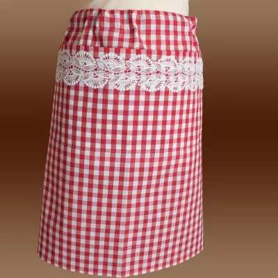 Ein rot-weiß karierter Rock mit geradem Schnitt und einem breiten horizontalen Band aus weißer Blumenspitze in der Nähe der Taille. Der Hintergrund besteht aus einem sanften Farbverlauf in Brauntönen. Der Rock ist an einer Schaufensterpuppe ausgestellt.
