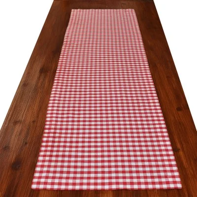 Ein Holztisch mit einem rot-weiß-karierten Tischläufer in der Mitte.
