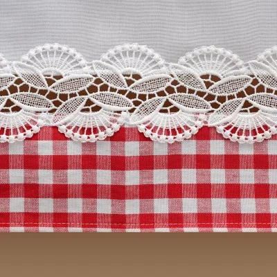 Nahaufnahme eines Stoffes mit weißer Spitzenborte über einem rot-weiß karierten Muster und einem braunen Streifen am unteren Rand. Die Spitze weist ein florales Wellenmuster auf, das im Kontrast zu den sauberen, kräftigen Karos des Gingham-Stoffes steht.