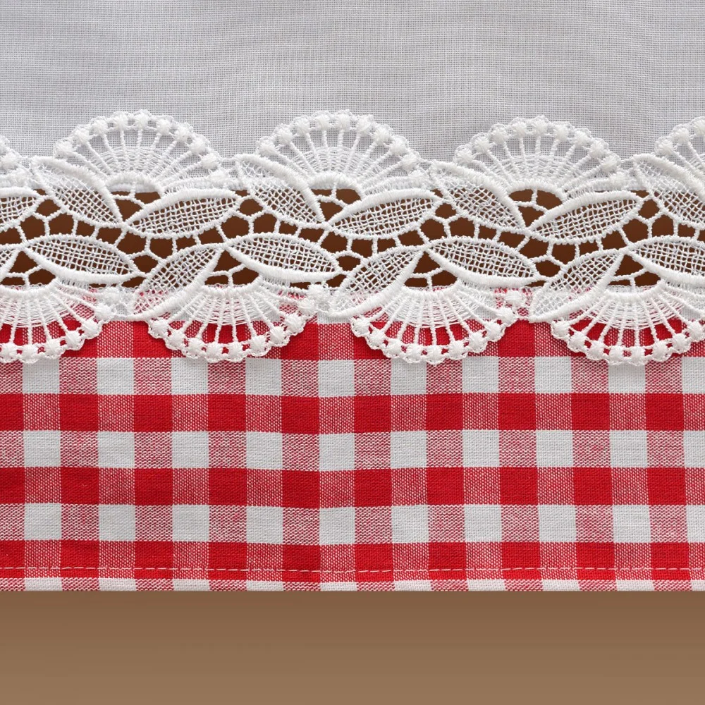 Nahaufnahme eines Stoffes mit weißer Spitzenborte über einem rot-weiß karierten Muster und einem braunen Streifen am unteren Rand. Die Spitze weist ein florales Wellenmuster auf, das im Kontrast zu den sauberen, kräftigen Karos des Gingham-Stoffes steht.