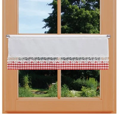 Ein holzgerahmtes Fenster mit einem kurzen weißen Vorhang mit Spitzenbesatz und roter Gingham-Bordüre hängt auf halber Höhe herab. Durch das durchsichtige Fensterglas sind üppige grüne Bäume und ein Garten zu sehen.