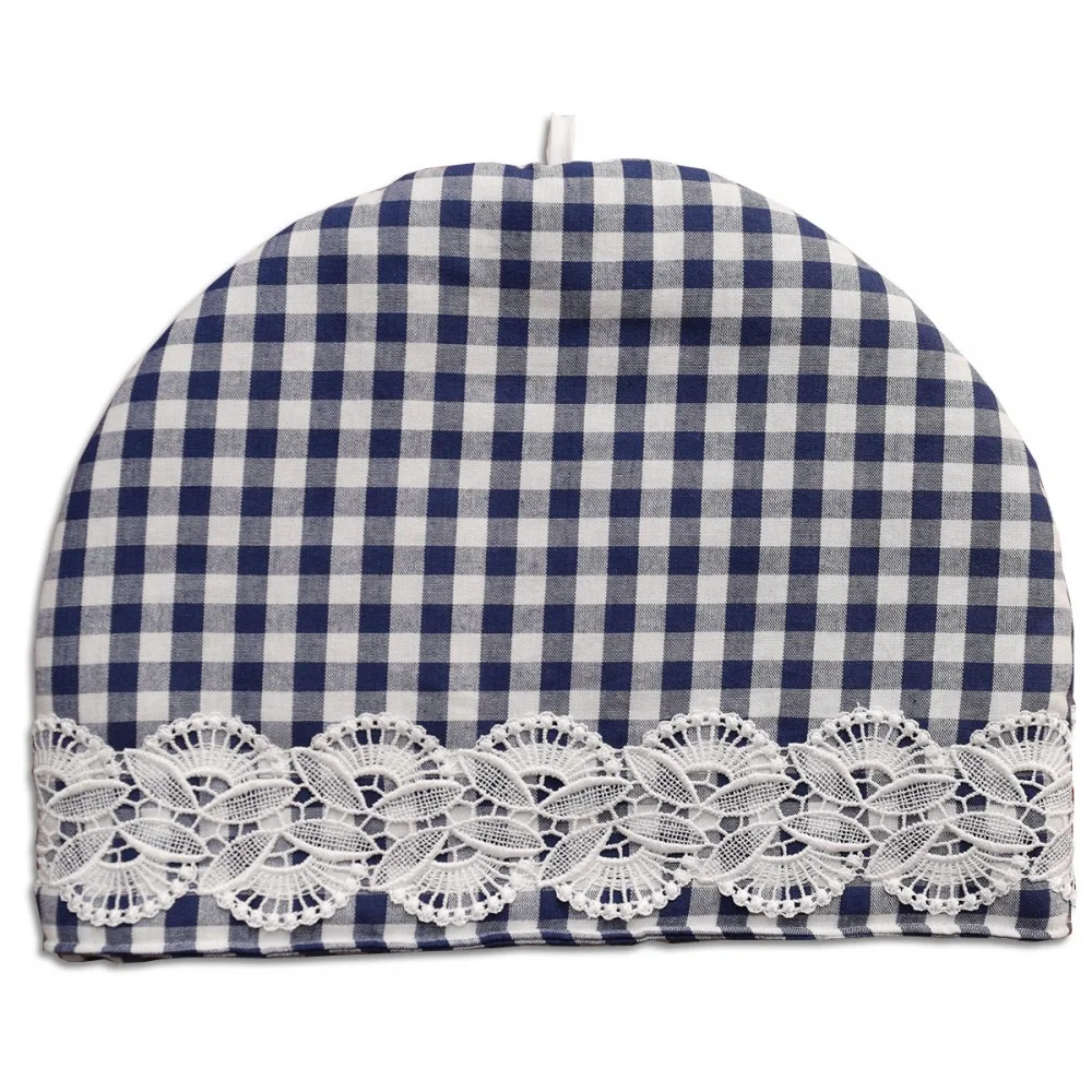 Ein blau-weiß karierter Teewärmer mit halbkreisförmiger Form. Er hat ein dekoratives Band aus weißer Spitze mit Blumenmuster im unteren Bereich und eine kleine Schlaufe am oberen Ende für die Handhabung.