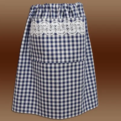 Eine blau-weiß karierte Schürze mit breitem, weißem Spitzenbesatz an der oberen Tasche, die am Bund gerafft ist und sich vor einem braunen Hintergrund mit Farbverlauf abzeichnet.