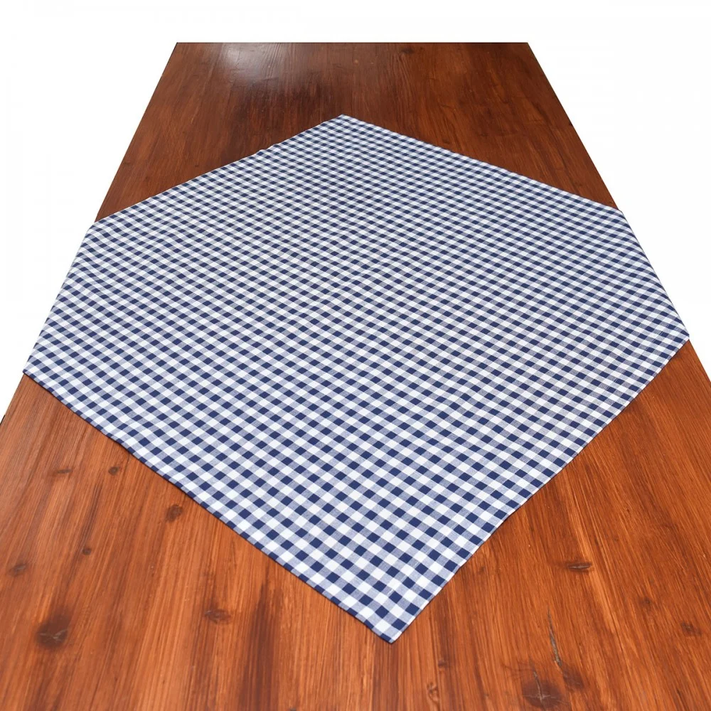 Ein Holztisch mit einer blau-weiß karierten Tischdecke, die diagonal in der Mitte ausgebreitet ist.