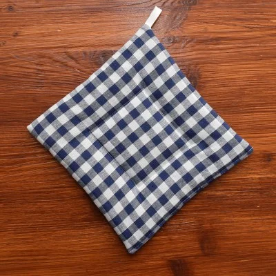 Ein blau-weiß karierter Topflappen aus Stoff mit einer kleinen Schlaufe zum Aufhängen, der auf einer Holzunterlage liegt.