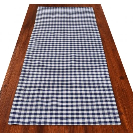 Ein rechteckiger Holztisch mit einem blau-weiß-karierten Tischläufer in der Mitte.