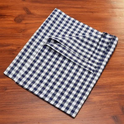 Eine gefaltete blau-weiß-karierte Stoffserviette liegt auf einer Holzplatte.