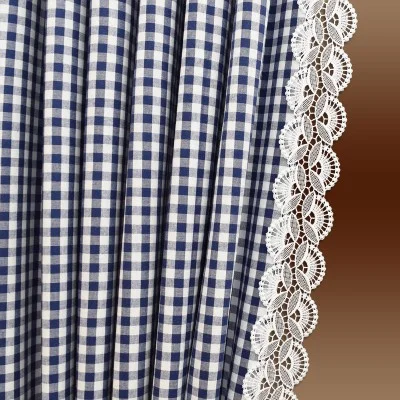 Blau-weiß karierter Stoff mit vertikalen Falten, rechts eingefasst von einer dekorativen weißen Spitzenborte mit Wellenschliff. Der Hintergrund geht von hell- zu dunkelbraun über.