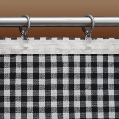 Ein schwarz-weiß karierter Vorhang hängt an einer silbernen Stange mit runden silbernen Haken mit klaren Plastikclips vor einem braunen Hintergrund. Der Vorhang hat ein einfaches Karomuster mit gleichmäßig verteilten Quadraten.