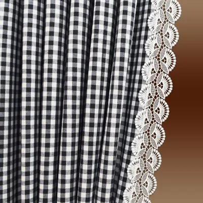 Schwarz-weiß karierter Stoff mit vertikalen Falten auf der linken Seite, auf der rechten Seite mit einer dekorativen weißen Spitzenborte eingefasst, vor einem braunen Hintergrund mit Farbverlauf.