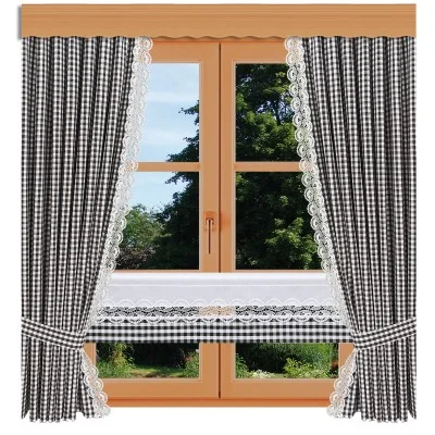 Ein holzgerahmtes Fenster mit schwarz-weiß karierten Vorhängen mit Spitzenbesatz und einem passenden kurzen Vorhang in der unteren Hälfte. Draußen sind grüne Bäume und Laub zu sehen.