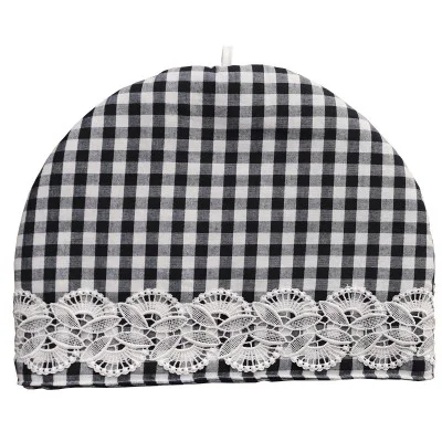 Ein schwarz-weiß karierter Teewärmer mit abgerundeter Oberseite. Der untere Rand ist mit einem breiten Streifen weißer Spitze mit floralem Muster verziert. In der oberen Mitte ist eine kleine weiße Schleife angebracht. Der Hintergrund ist einfarbig und weiß.