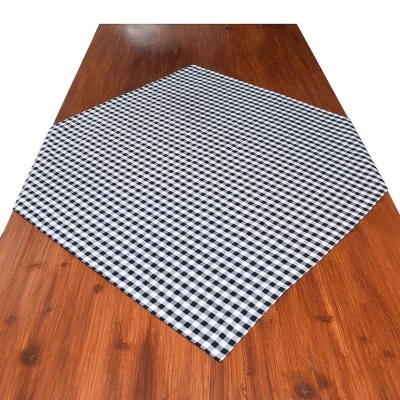 Ein brauner Holztisch mit einem schwarz-weiß karierten Tischtuch, das diagonal über die Mitte gelegt ist.