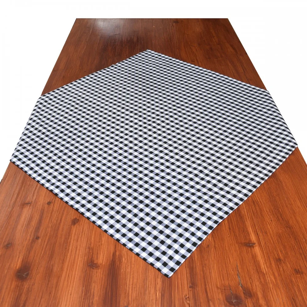 Ein brauner Holztisch mit einem schwarz-weiß karierten Tischtuch, das diagonal über die Mitte gelegt ist.
