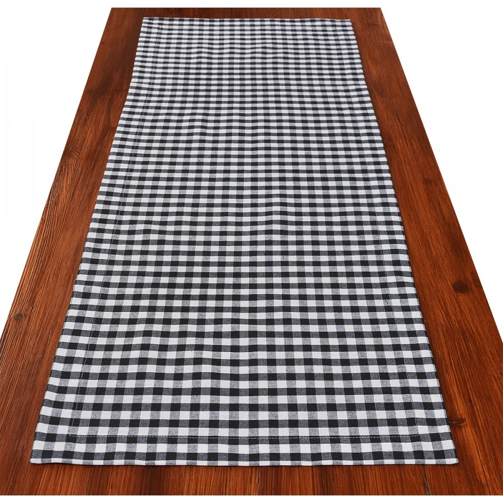 Ein schwarz-weiß karierter Tischläufer ist auf einem Holztisch ausgebreitet.