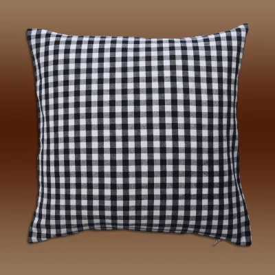 Ein quadratisches Kissen mit einem schwarz-weiß karierten Muster auf dem Stoff vor einem Hintergrund mit braunem Farbverlauf.