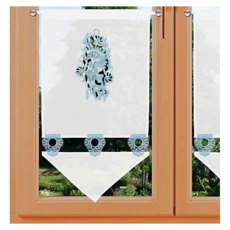 Ein Fenster mit Holzrahmen und weißen Spitzenvorhängen mit aufwendiger blauer Stickerei - Seepferdchen aus Plauener Spitze. Die Vorhänge haben eine rautenförmige untere Borte und werden von oberen an einer Gardinenstangen gehalten, wodurch ein klassischer Look entsteht, der an einen maritimen Scheibenhänger erinnert. Der Blick nach draußen umfas