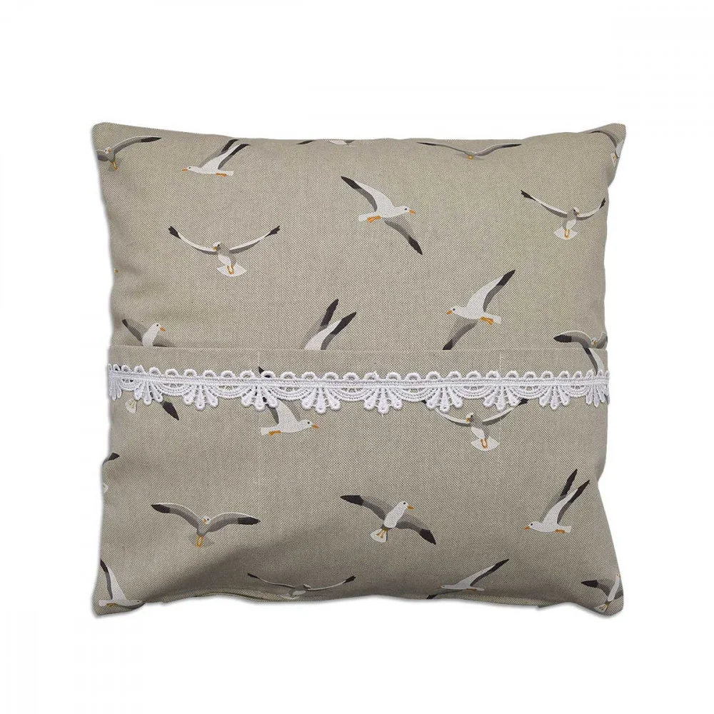 Ein quadratisches beiges Kissen (40 x 40 cm) mit einem Muster aus Möwen in verschiedenen Flugposen. Eine weiße dekorative Spitzenbordüre verläuft horizontal über die Mitte des Kissens. Der Hintergrund ist einfarbig und hebt die Vogelillustrationen und die Spitzenverzierung hervor.