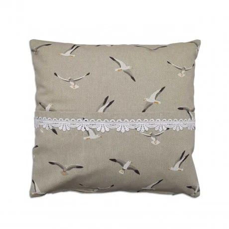Ein quadratisches beiges Kissen (40 x 40 cm) mit einem Muster aus Möwen in verschiedenen Flugposen. Eine weiße dekorative Spitzenbordüre verläuft horizontal über die Mitte des Kissens. Der Hintergrund ist einfarbig und hebt die Vogelillustrationen und die Spitzenverzierung hervor.