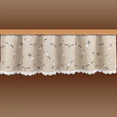 Der beigefarbene Fensterbehang zeigt ein Muster aus fliegenden Vögeln in Weiß, Grau und Schwarz. Der Stoff hat einen leicht gewellten Faltenwurf und ist am unteren Rand mit einer weißen Spitzenborte versehen. Der Hintergrund ist ein brauner Farbverlauf.