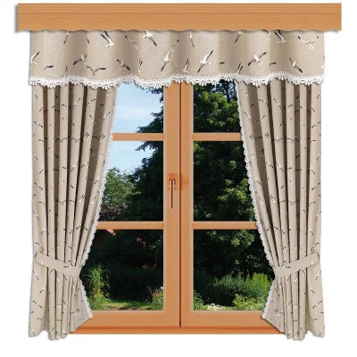An einem holzgerahmten Fenster hängen zwei beigefarbene Vorhänge und ein passender Volant, die jeweils mit kleinen schwarzen Vogelmustern verziert und mit weißer Spitze eingefasst sind. Die Vorhänge sind zurückgebunden und zeigen einen Garten mit grünem Laub und Bäumen im Sonnenlicht.
