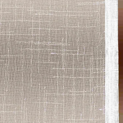 Eine Nahaufnahme eines weißen Gewebes mit grober Textur. Das Material scheint ein gitterartiges Muster aufzuweisen, das durch die sich kreuzenden Fäden entsteht. Am rechten Rand ist ein weißer Rand zu sehen, der vertikal entlang des Stoffes verläuft.