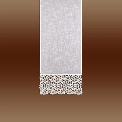 Ein vertikal aufgehängtes weißes Stoffpaneel mit einer dekorativen Kante aus einem komplizierten Spitzenmuster an der Unterseite, vor einem braunen Hintergrund mit Farbverlauf.