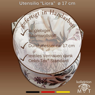 Ein handgefertigter Utensilienhalter aus Stoff mit floralem Muster, beschriftet mit „Liora“ (Ø 17 cm). Er besteht aus strapazierfähigem Baumwollstoff und ist nach Öko-Tex Standard zertifiziert. Der Text ist auf Deutsch und enthält Beschreibungen und Häkchen.