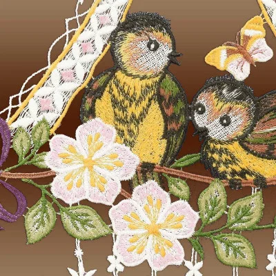 Stickerei von zwei Vögeln auf einem Ast, geschmückt mit rosa und gelben Blüten, grünen Blättern und einem Schmetterling darüber. Vor einem braunen Farbverlauf zeigt dieses Fensterbild die für die Vogtländische Spitze typische, aufwendige Stickerei.
