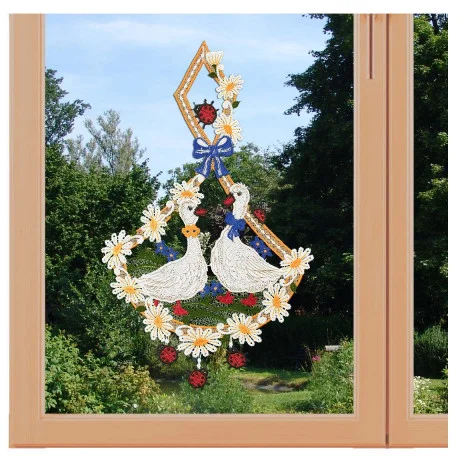 Ein bezauberndes Fensterbild zeigt exquisite Vogtländische Spitze mit zwei weißen Enten inmitten von Blumen, Beeren und einer blauen Schleife. Es hängt anmutig an einem hellen Holzfenster und rahmt die idyllische Landhaus-Idylle mit grünen Bäumen und Sträuchern dahinter ein.