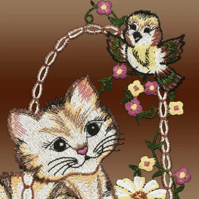 Stickerei eines niedlichen Kätzchens und eines Vogels, umgeben von Blumen auf einem braunen Hintergrund mit Farbverlauf. Die Katze blickt verspielt auf den Vogel, der auf einem Korb sitzt, der mit rosa und gelben Vogtländischen Spitzenblumen geschmückt ist, wodurch eine filigrane Fensterbildszene entsteht.