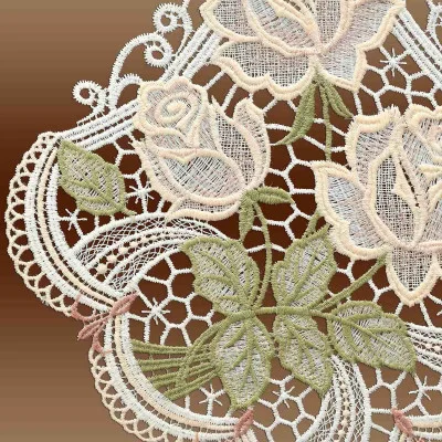 Aufwendige Spitzenstickerei mit floralen Motiven aus Rosen und Blättern in sanften Pastelltönen auf braunem Hintergrund. Dieses Vogtländische Spitzenmuster erzeugt ein zartes und elegantes Erscheinungsbild, das an einen zeitlosen Rosenstrauß erinnert.
