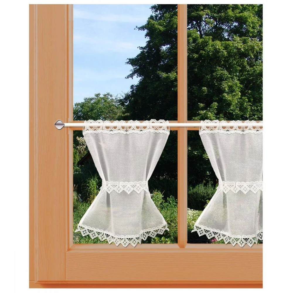 Ein Fenster mit Holzrahmen und in der Mitte zusammengebundenen weißen Spitzenvorhängen bietet an einem sonnigen Tag den Blick auf grüne Bäume und Büsche draußen.