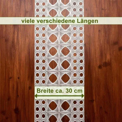 Eine Flächengardine aus weißer Spitze mit geometrischen Mustern liegt auf einer dunklen Holzoberfläche. Der Text auf Deutsch lautet „viele verschiedene Längen“ und „Breite ca. 30 cm“, wobei Pfeile die Breite angeben.