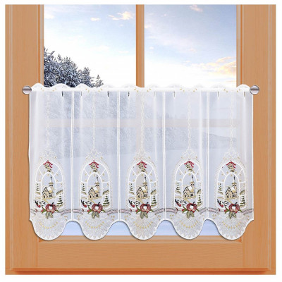 Ein kurzer, dekorativer weißer Vorhang aus Vogtländischer Spitze mit gestickten Vögeln, Äpfeln und Kirchenfenstermotiven hängt an einem Holzrahmen. Draußen sorgt eine sonnige Winterlandschaft für die perfekte Adventsfenster-Stimmung.